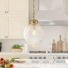 a kitchen with white cabinets and an island in front of the countertop is lit by a golden chandelier