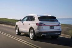 the rear end of a white porsche cayen driving down a road near the ocean