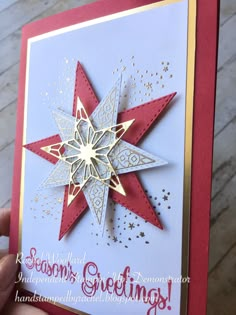 someone is holding up a christmas card with a star on the front and bottom corner