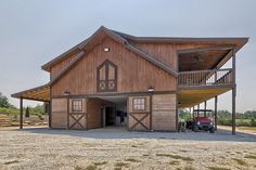 a large wooden barn with a car parked in the driveway