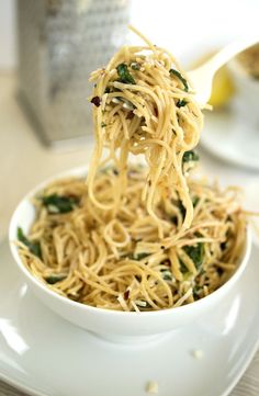 a white bowl filled with noodles and spinach