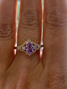 a woman's hand with a ring on it and a purple stone in the middle