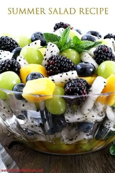 a glass bowl filled with fruit salad on top of a wooden table