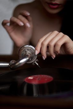 a woman's hand on top of a record player with her finger resting on the turntable