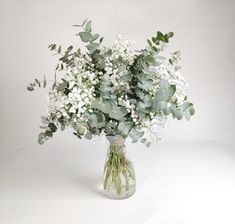 a vase filled with white flowers and greenery