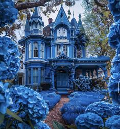 a blue house surrounded by flowers and trees