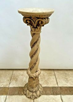 an ornately decorated pedestal stands on a tiled floor