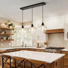 a kitchen with wooden cabinets and white counter tops, hanging lights over the stove top