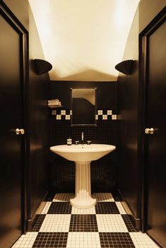 a bathroom with black and white tiles on the floor, sink and mirror in it