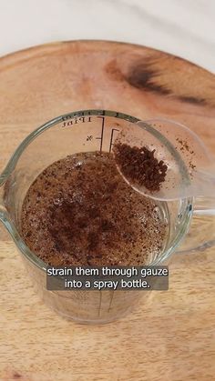 a measuring cup filled with brown stuff on top of a wooden table