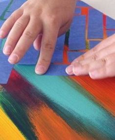 a child's hand on top of a piece of art paper with colored paint