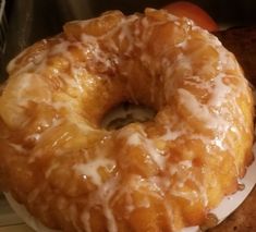 a glazed donut sitting on top of a white plate next to an orange apple