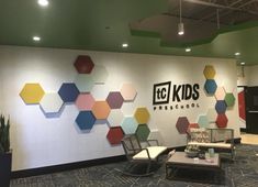 an office lobby with colorful hexagonal tiles on the wall and chairs in front of it