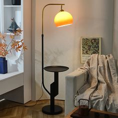 a living room with a couch, table lamp and bookshelf in the corner