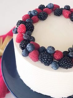 a white cake with berries and blueberries on top