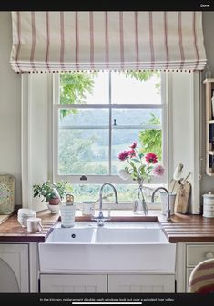 a kitchen sink sitting under a window next to a wooden counter top with dishes on it