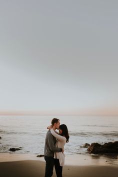 an engaged couple embracing on the beach