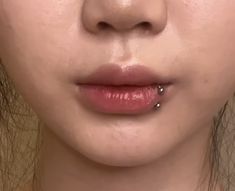 a close up of a woman's face with piercings on her lip and nose