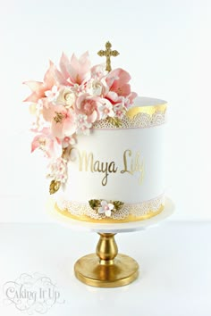 a white and gold cake with pink flowers on top that says mary lily in gold lettering