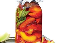 a glass jar filled with sliced peaches and mint