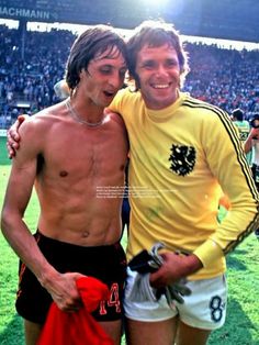 two young men standing next to each other on a field with fans in the background