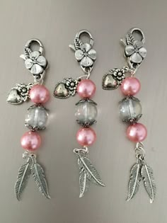 three pairs of earrings with pink beads and silver leaves on the end of each ear