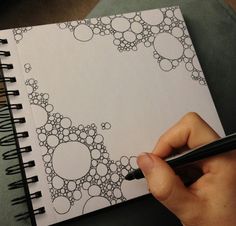 a hand holding a pen writing on top of a notebook with circles drawn on it