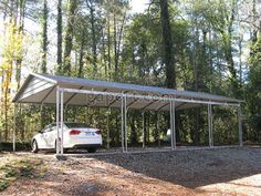 a white car parked under a metal carport in the middle of a wooded area