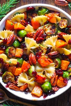 a white bowl filled with pasta and veggies on top of a wooden table