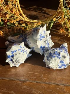 three blue and white vases sitting on top of a wooden table next to dried flowers