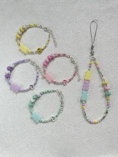 four bracelets with beads and charms hanging from them on a white tablecloth background