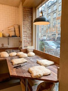 bread is being prepared on a wooden table in a room with brick walls and windows