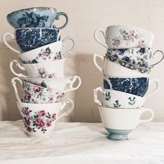 a stack of tea cups sitting on top of a white bed next to each other