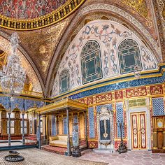 the inside of an ornate building with chandeliers and paintings on the walls,