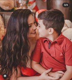 a mother and son cuddle together in front of a teddy bear at christmas time