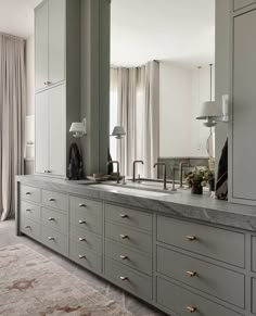 a kitchen with gray cabinets and marble counter tops