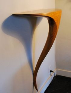 a curved wooden shelf against a white wall