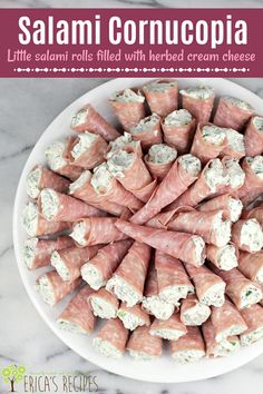 a white plate topped with rolls covered in cream cheese and garnished with prosciutto