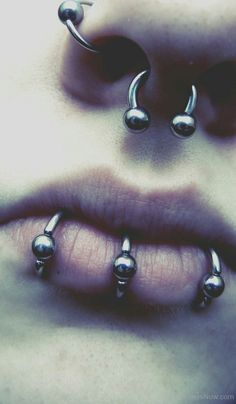 a woman's nose with three balls attached to her lip and two piercings