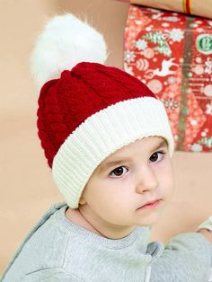 a young boy wearing a red and white hat with a pom - pom