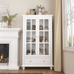 a living room with a fire place next to a white china cabinet and a fireplace