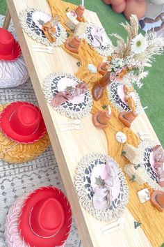 a wooden table topped with lots of plates and red hats on top of each other