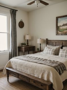 a bed sitting under a window in a bedroom next to two lamps and a painting on the wall