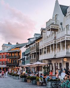 many people are sitting at tables in front of buildings