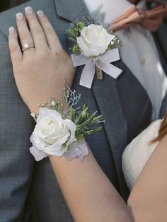 the bride and groom are holding hands with flowers in their lapel covers on their wedding day