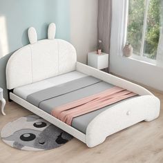 a white bed sitting on top of a hard wood floor next to a dresser and window