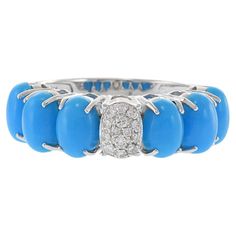 This 18KT white gold ring is a unique and elegant piece featuring six genuine oval cabochon turquoise stones arranged in a captivating design. At the center, a pave diamond link adds a touch of sparkle with 0.10 carats total weight of G color and VS1-VS2 clarity round-cut diamonds. The combination of the vivid turquoise and the brilliant diamonds creates a harmonious and eye-catching contrast, making this ring a sophisticated addition to any jewelry collection. Size 6.75 US. Weight 5.6 gm. Luxury Artisan Turquoise Oval Ring, Turquoise And Diamond Ring, Turquoise Diamond Rings, Oval Rings, Turquoise Stones, White Gold Ring, Brilliant Diamond, Oval Cabochon, Round Cut Diamond