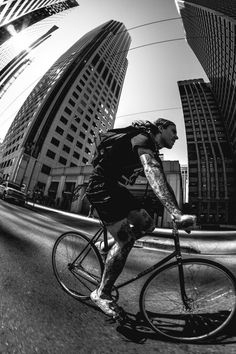 a man riding a bike down the middle of a street next to high rise buildings