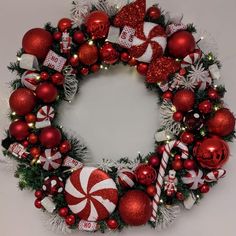 a christmas wreath with ornaments and candy canes on the front, surrounded by tinsel