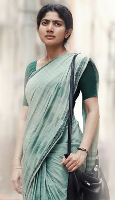 a woman in a green sari holding a black purse